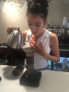 Prevención de cáncer de colon con café; barista experta preparando café especialidad con la aeroprés